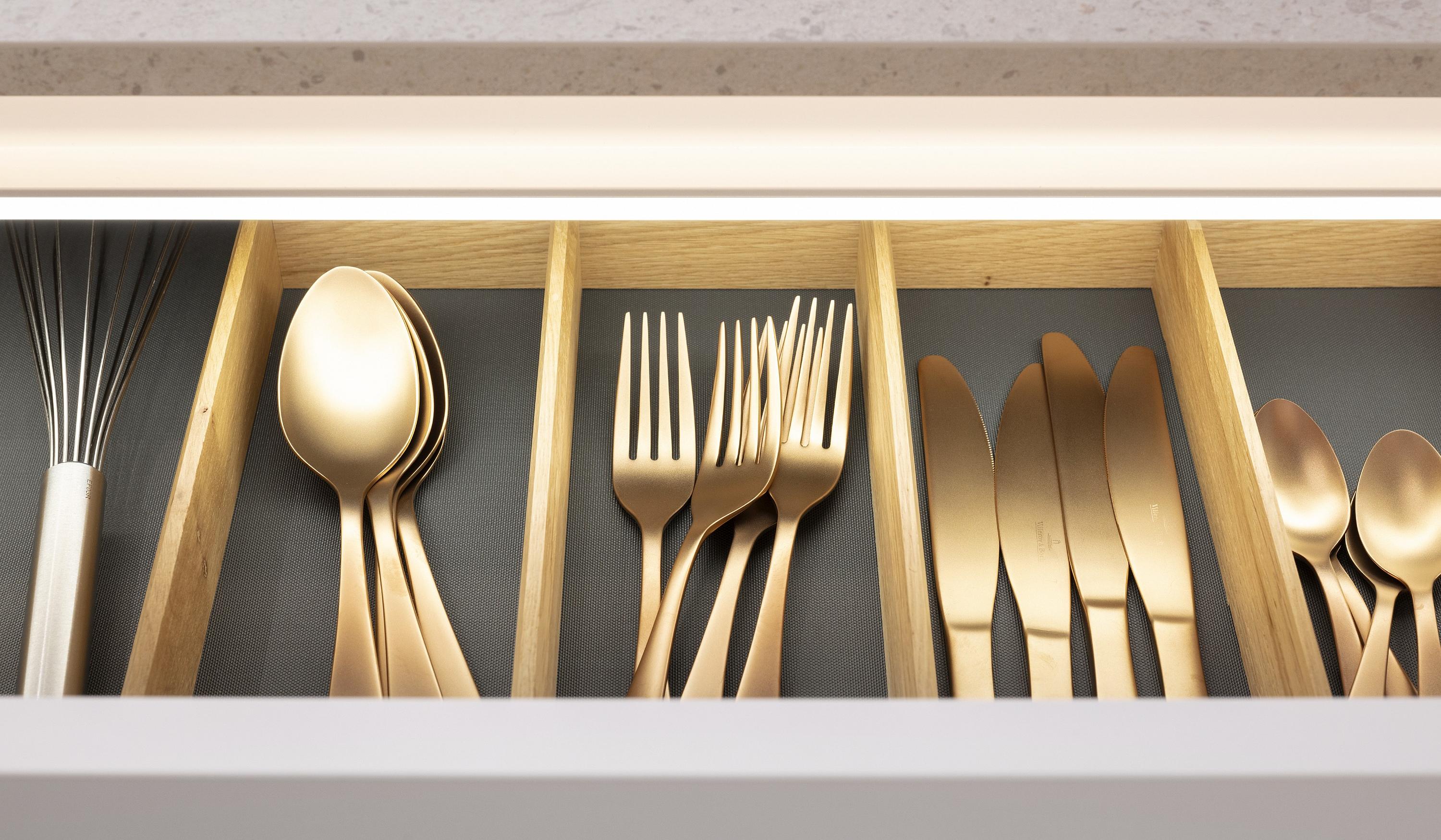 Goldenes Besteck in einer halb geöffneten Besteck-Schublade in einer Nobilia Küche