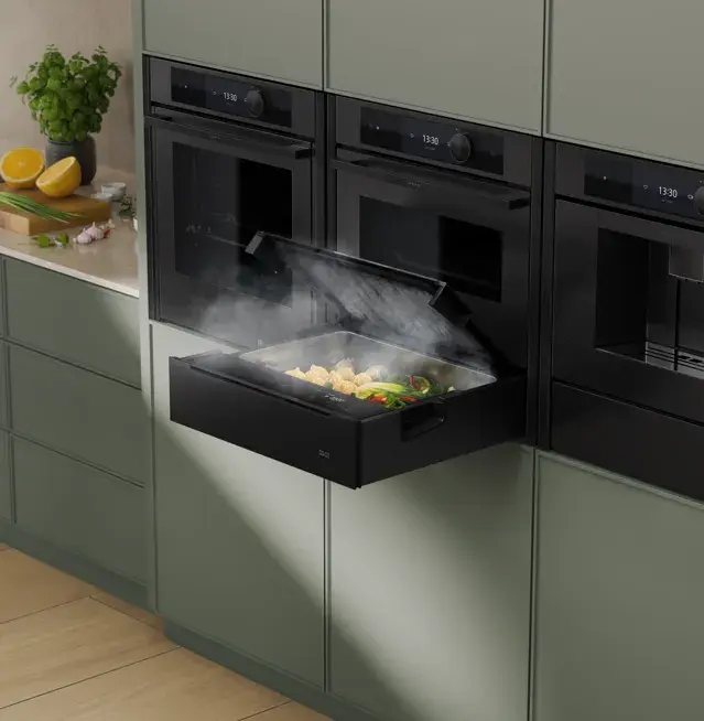 Dampfgarer mit geöffnetem Fach, darin dampfendes Gemüse in moderner Küche